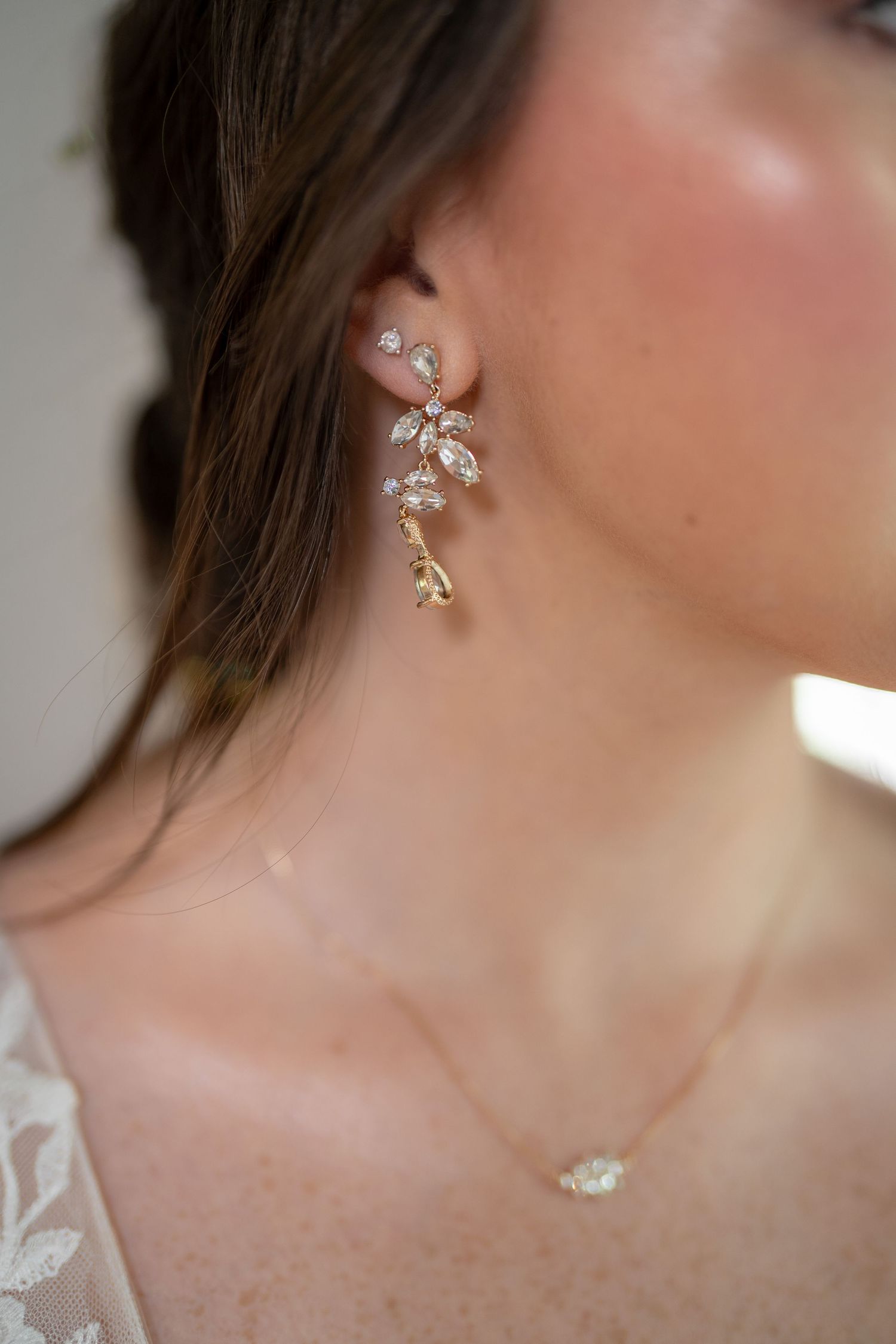 Close-up of delicate crystal floral drop earring and necklace on bride.