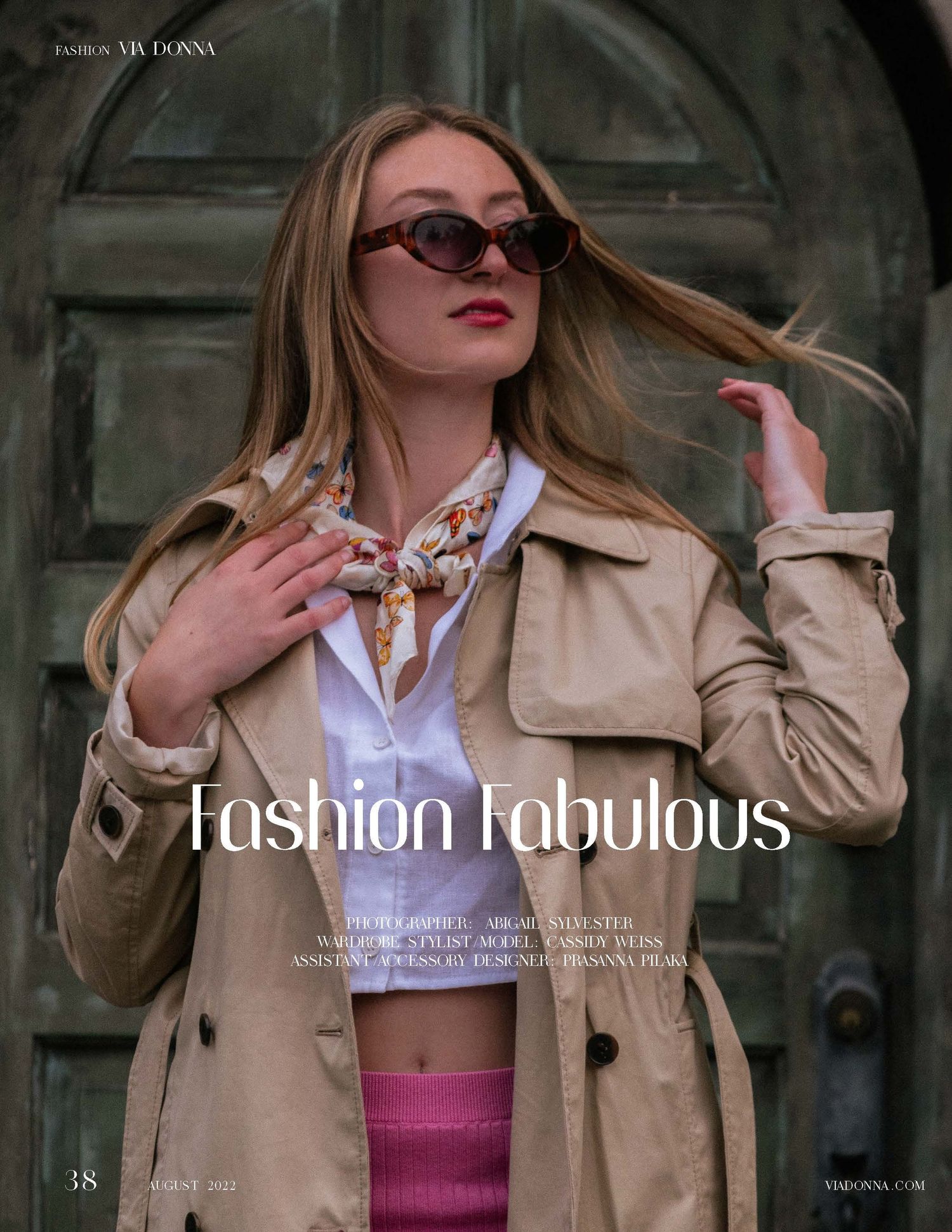 Stylish model in trench coat and sunglasses poses dramatically against vintage doorway.