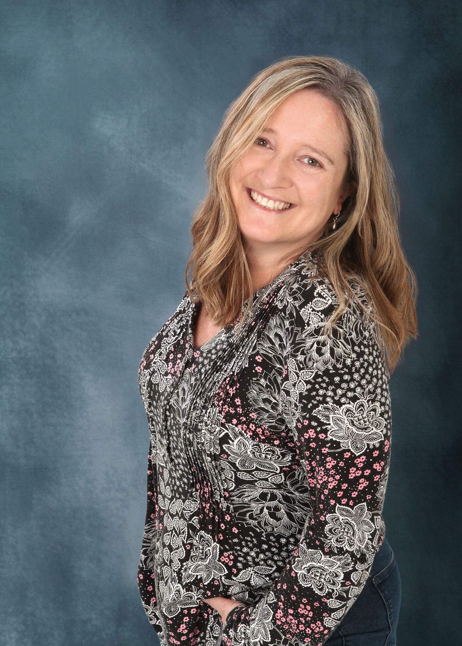 Person wearing a black and white patterned top with floral designs poses against a textured blue backdrop.