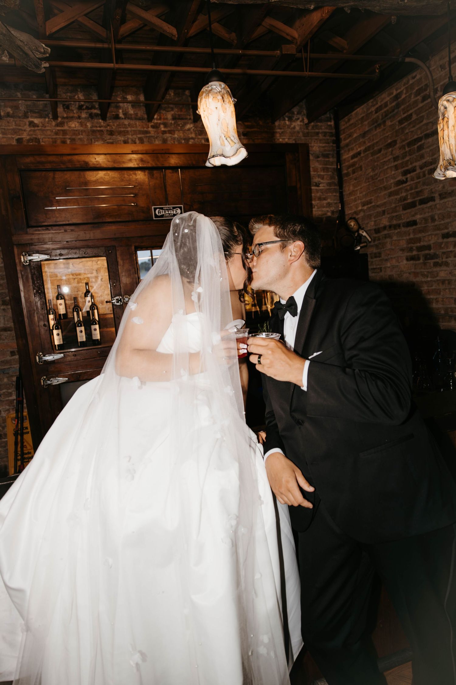 Bride and groom sharing a champagne kiss inside The Haight venue with warm rustic decor.