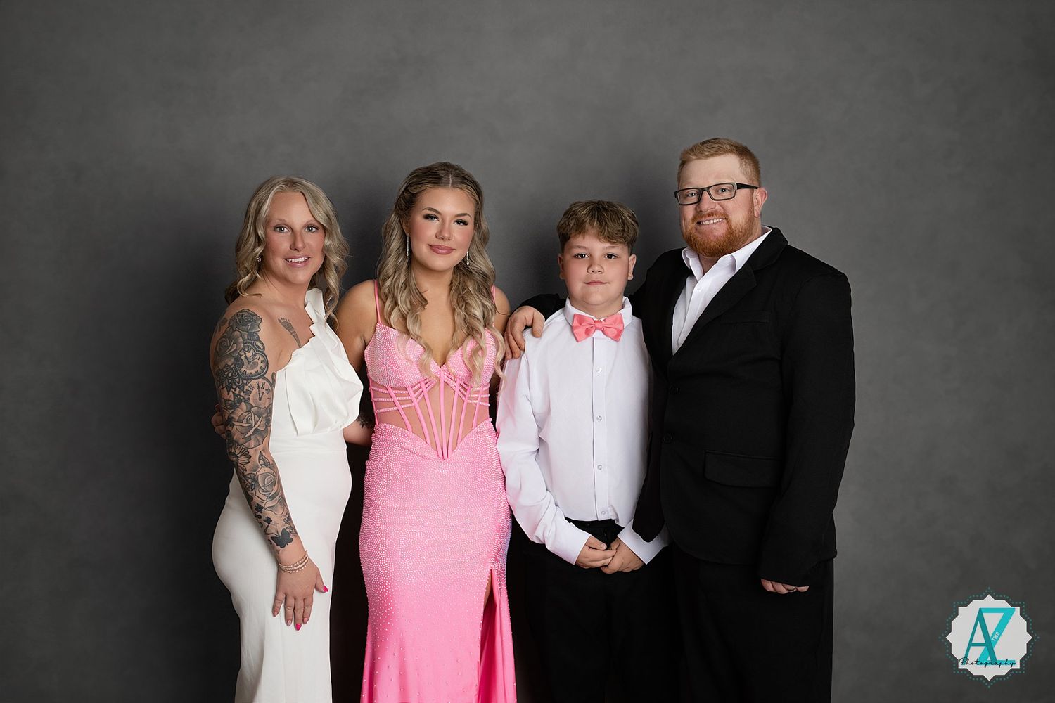 A formal group portrait in a studio setting against a gray background.