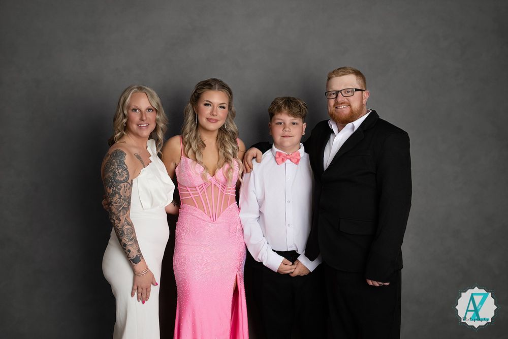 A formal group portrait in a studio setting against a gray background.