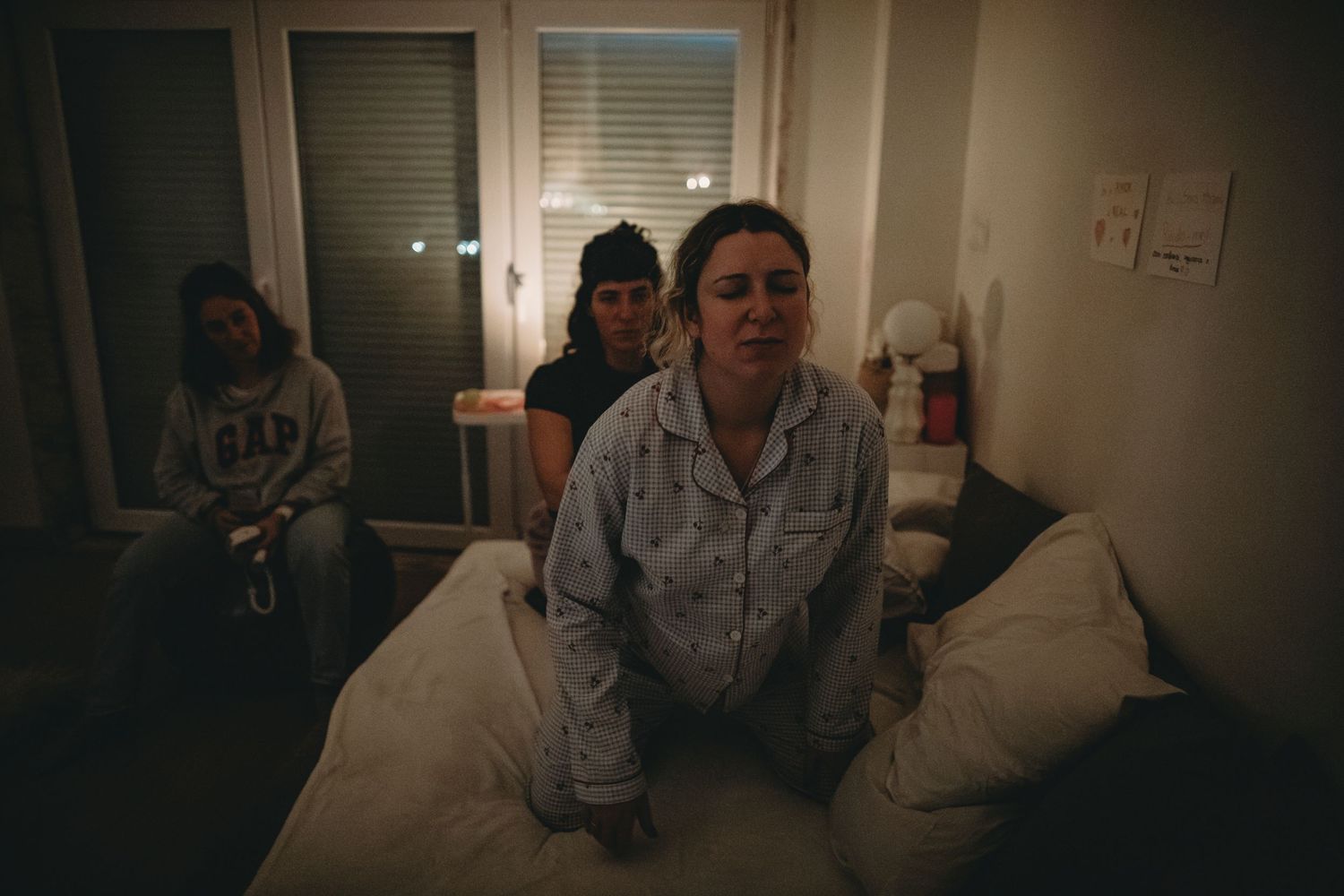 foto colorida durante parto domciliar em Lisboa, grávida durante contração recebe massagem da doula, parteira olha