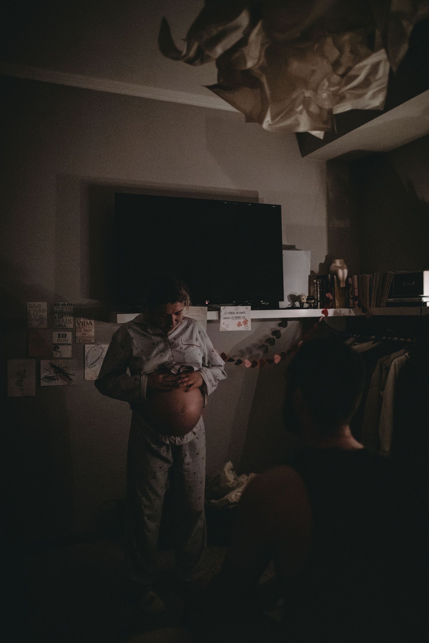 foto colorida durante parto domiciliar em Lisboa, mãe em pé no quarto a olhar para a barriga
