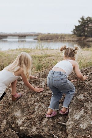 cousins climbing rocks during playful candid photography session in Shediac photographer New Brunswick family photographer