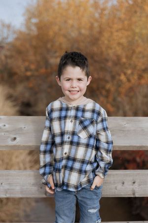 Son poses in front of a stream in an outdoor fall family photoshoot, family portraits lifestyle photography in Moncton New Brunswick Canada