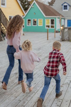 mom and kids run through colourful wharf in New Brunswick, Moncton lifestyle photographer family portraits in Dieppe NB, maritime photos