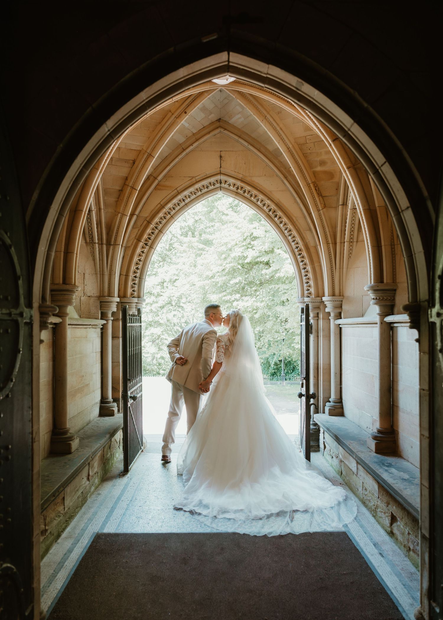 Romantic wedding photos captured in a gothic stone archway corridor.
