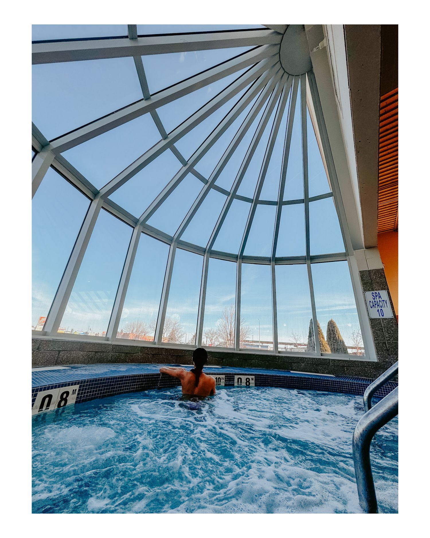 Indoor pool with glass dome ceiling offering panoramic sky views and bubbling hot tub water.