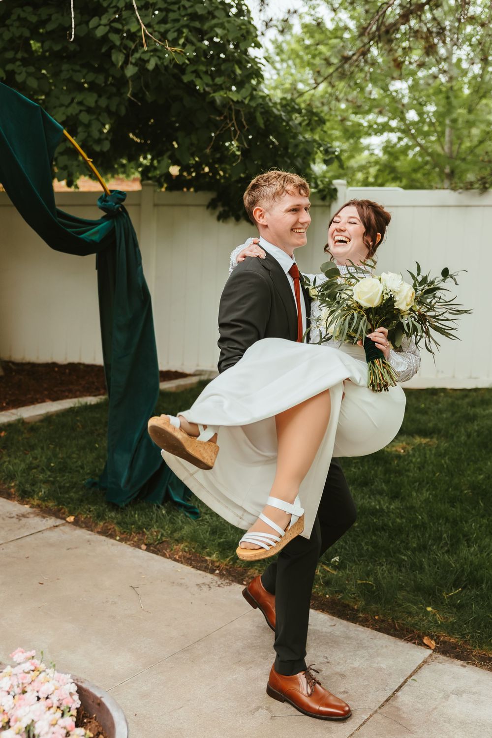 A joyful wedding couple shares a candid moment as the groom lifts the bride in her white dress.
