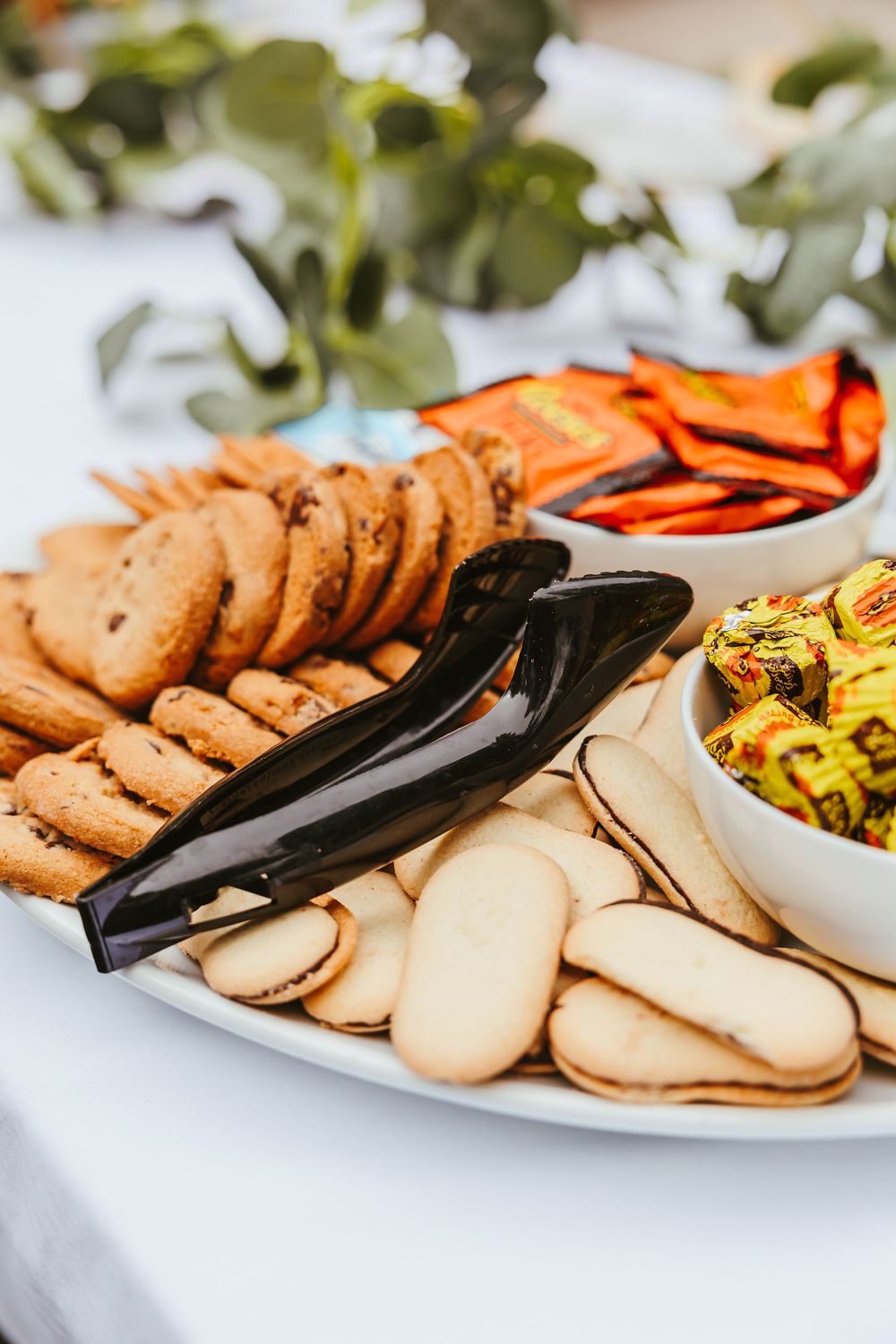 An appetizer platter with assorted cookies and snacks arranged on white plates.
