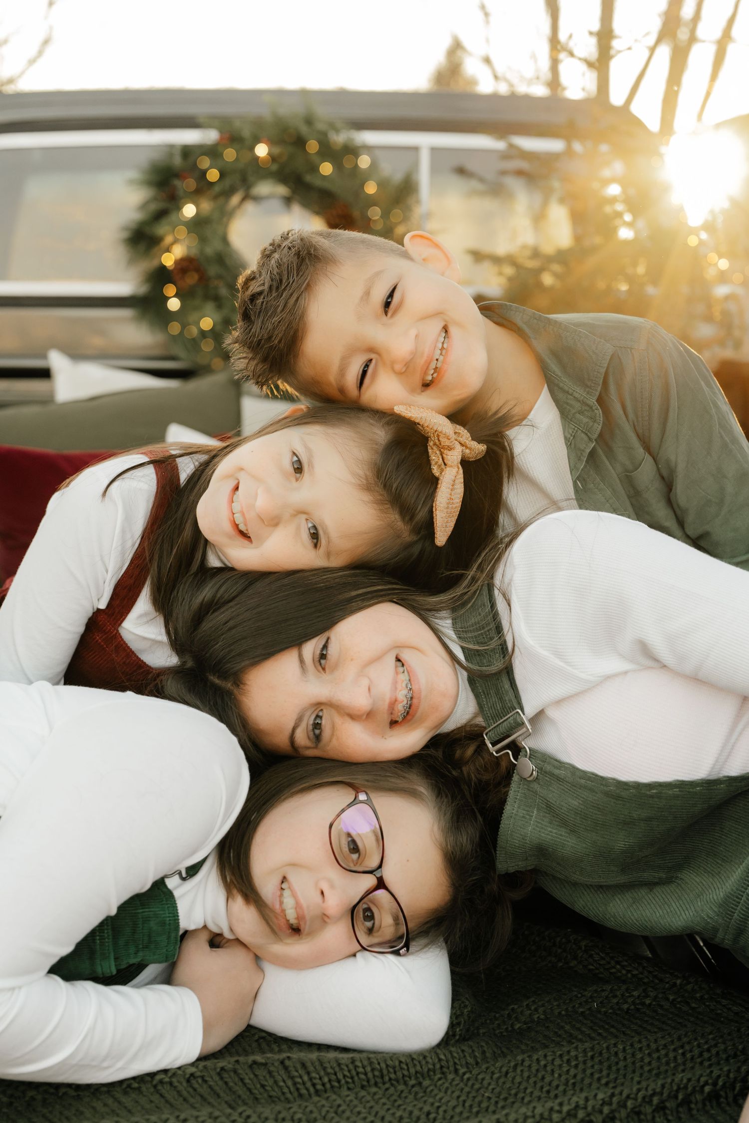 A family of four snuggled together on a blanket with holiday decorations visible.