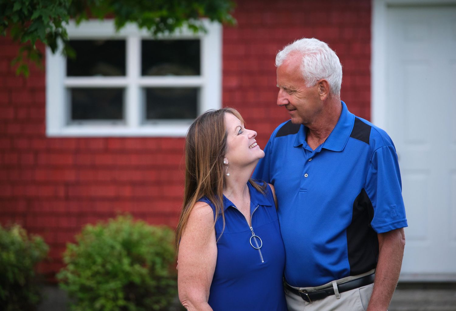 A couple stands and looks into each other's eyes for a family portrait on their Wisconsin farm.