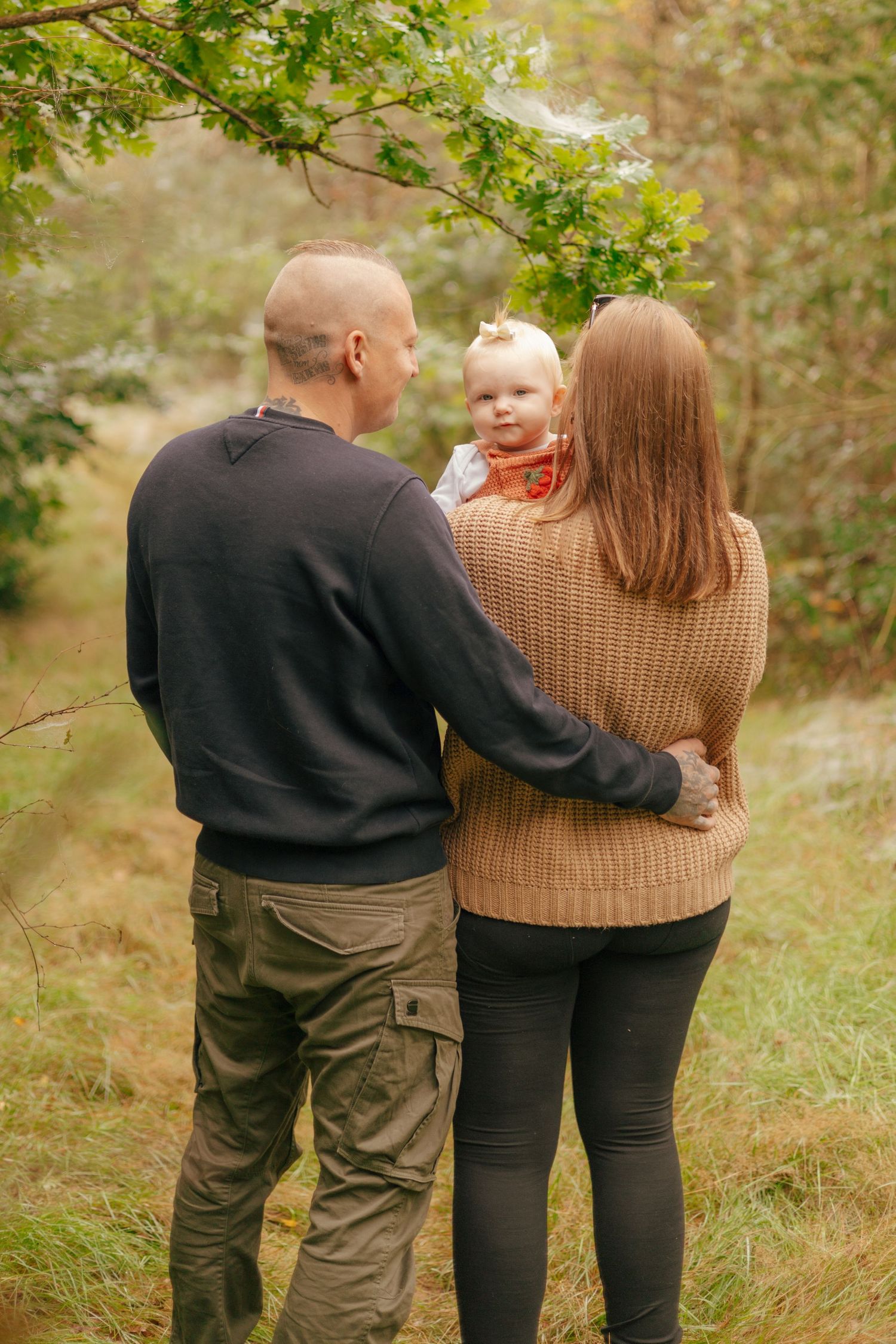 Family stands together admiring nature on an autumn day in the woods.