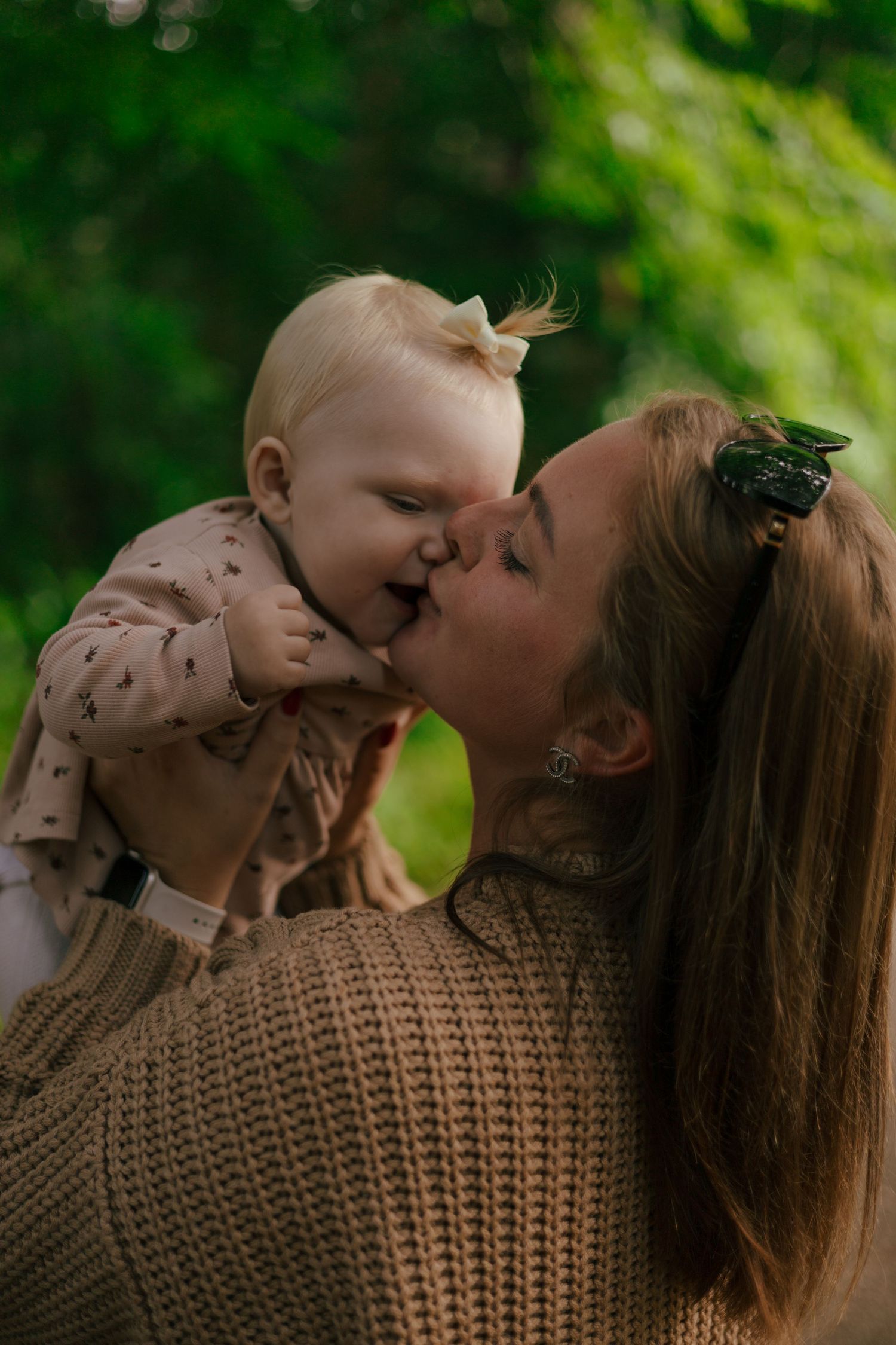 A tender moment captured in a sunlit outdoor setting showing nurturing care and affection.