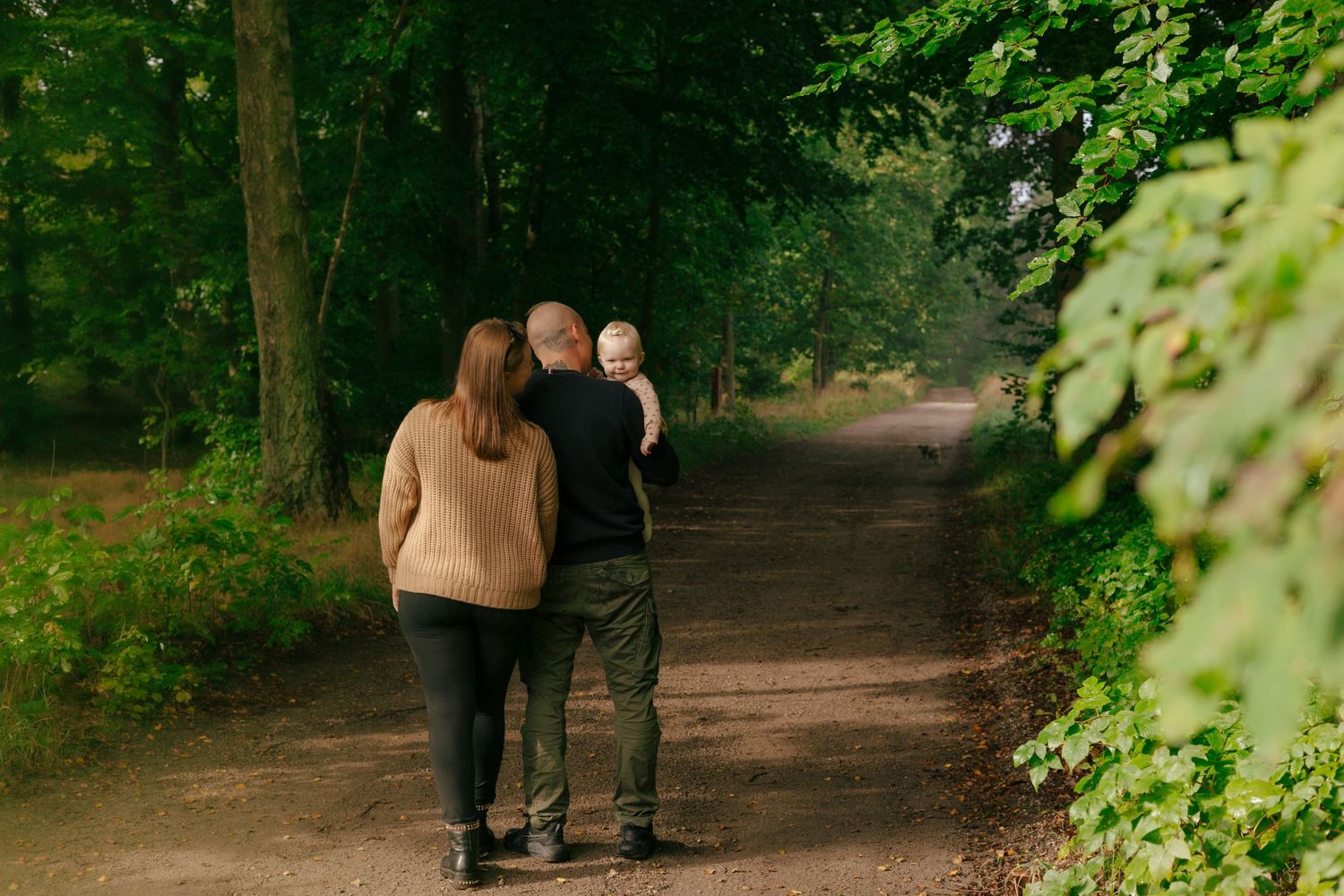 Two people walking together on a tree-lined path on an autumn day.