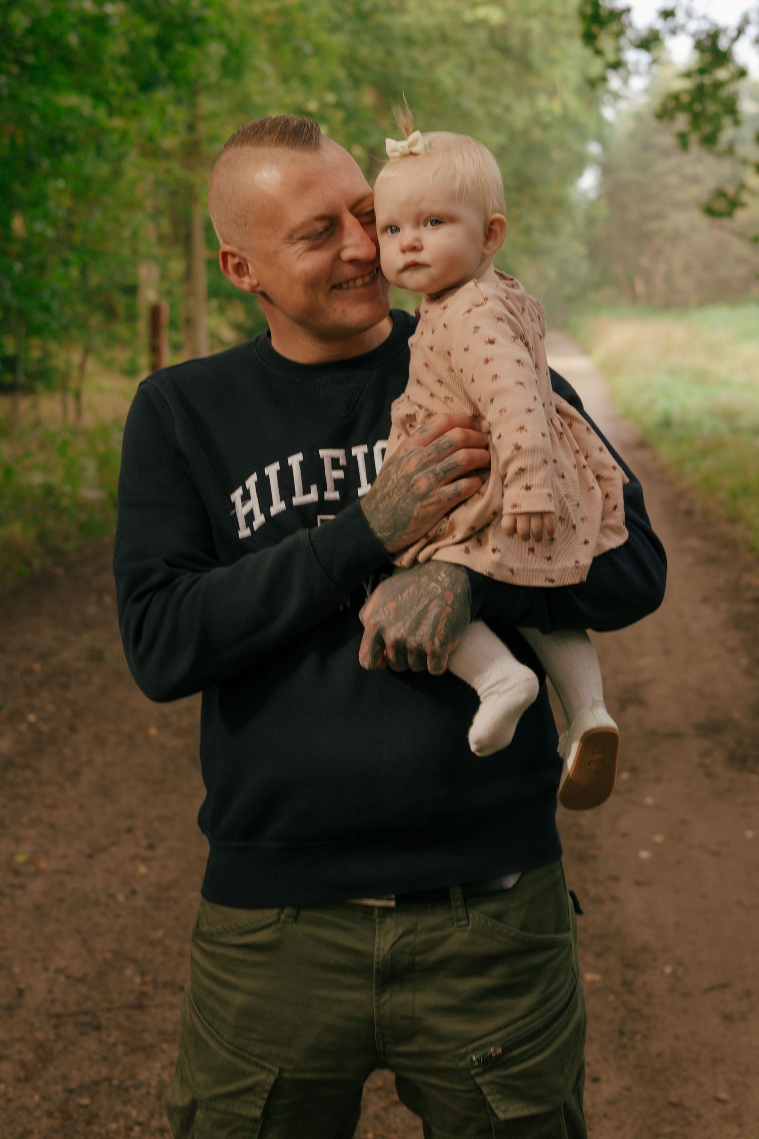 A heartwarming outdoor portrait showing affectionate interaction in casual wear against a natural background.