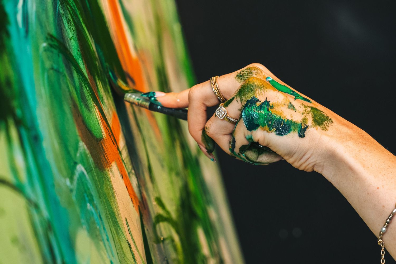 Close-up detail of artist’s hand painting on canvas