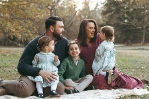 A family sits together on a blanket outdoors during autumn, sharing joyful moments in a park setting. Durham Forest Hills Park