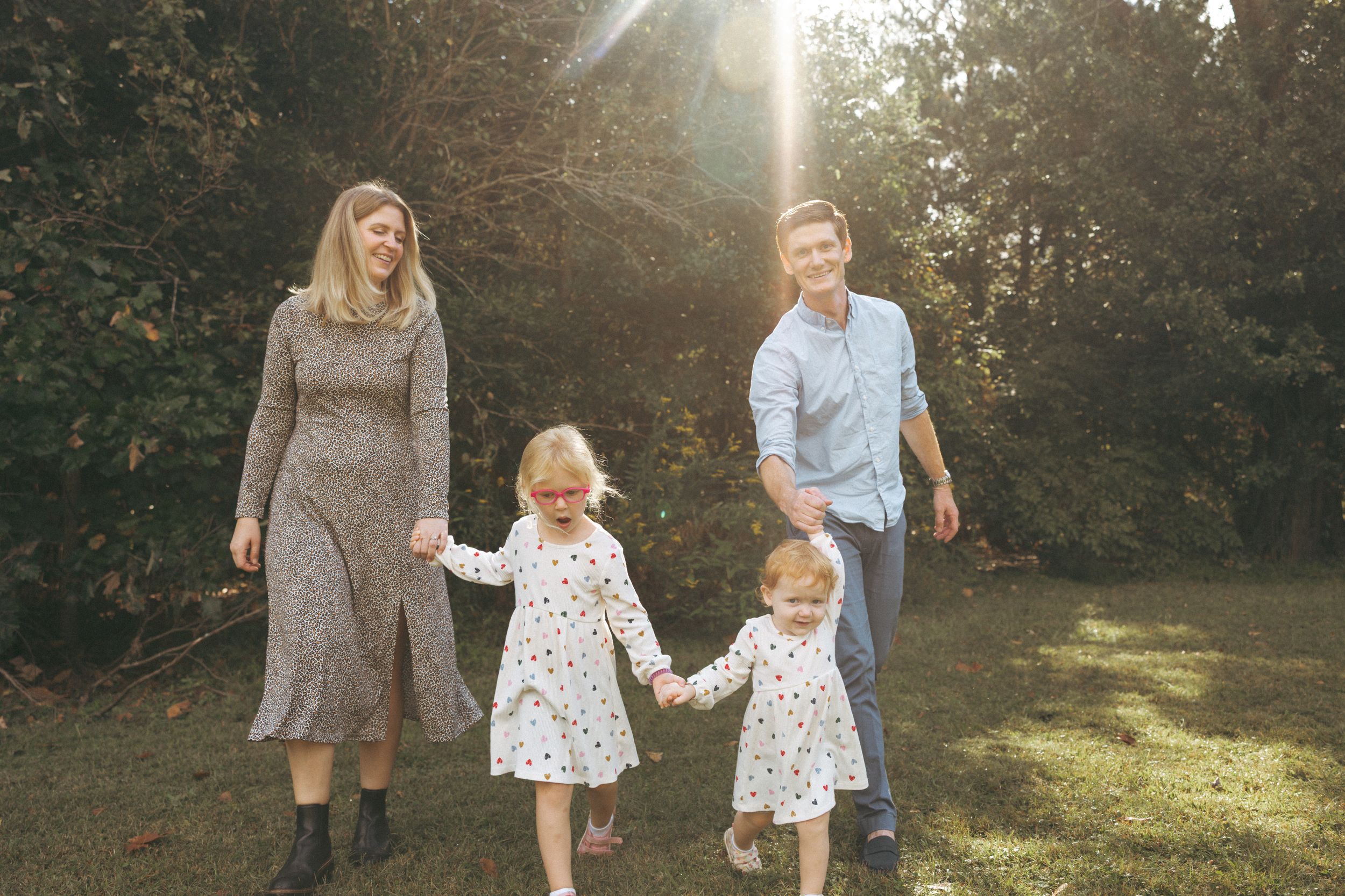 Family walking together through a sunlit park during golden hour.