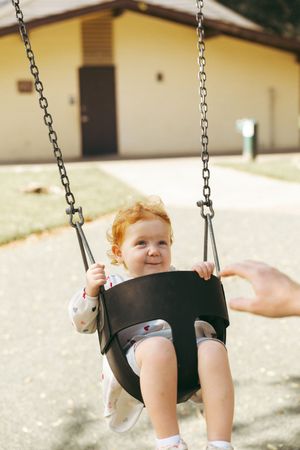 Baby enjoying a swing ride outdoors on a sunny day.