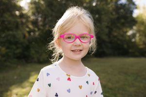 A series of outdoor portraits showing someone in pink glasses and a heart-patterned shirt against a natural background.