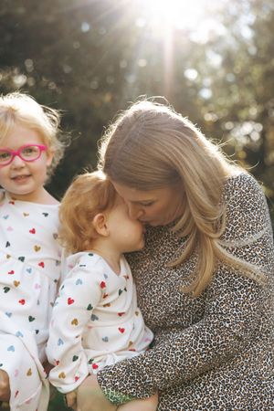 A tender outdoor family moment captured in sunlight with heart-patterned pajamas and a leopard print dress.