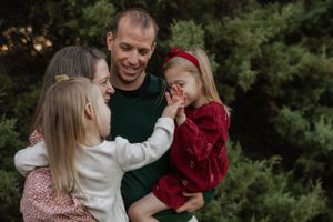 Family outdoor portrait with green sweater and festive holiday outfits.