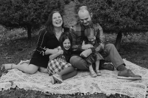 A family enjoying a picnic together on a lace blanket in black and white.