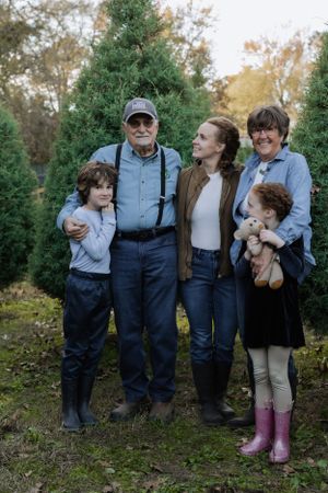 A group photo outdoors with evergreen trees in the background and a stuffed animal toy.