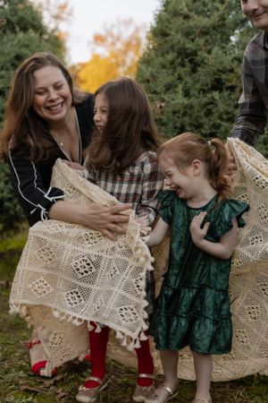 A joyful family moment outdoors examining vintage lace fabric together against autumn trees and foliage.