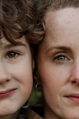 An intimate close-up portrait showing two faces side by side outdoors.