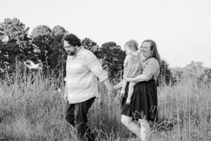 A family shares a tender moment together in a field of tall grass.