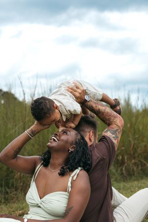 A joyful couple sharing an intimate moment outdoors against a cloudy sky.