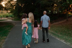 Family walks together on a path during sunset in a park.