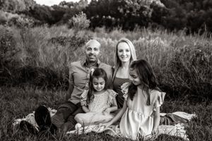 Black and white portrait of a family sitting together on a blanket in a meadow.