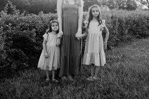 Three people in flowing dresses pose together for a classic black and white portrait.