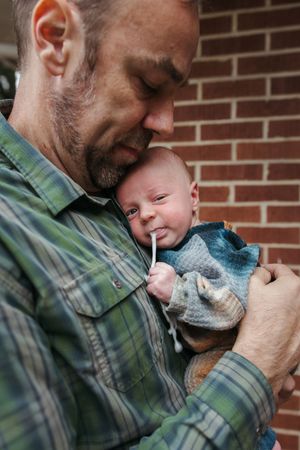 Progressive photos of an intimate bonding moment between adult and infant against brick wall background.