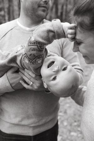 A black and white candid photo captures a playful family moment outdoors.