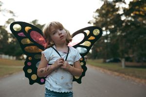 Photo sequence of a young child playing outdoors with butterfly wings.
