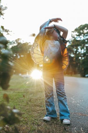 Low angle view of legs walking on path at sunset with lens flare creating dreamy golden light effect.