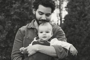A black and white photo series showing tender moments between a parent and baby in an outdoor setting.
