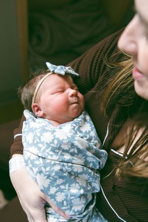 A series of photos showing a swaddled newborn baby in a blue and white patterned blanket being cradled.