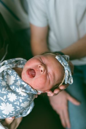 A sleeping newborn baby wearing a blue and white floral patterned outfit is photographed from multiple angles.