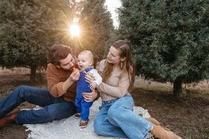 A family enjoying a sunny afternoon together outdoors on a blanket during a golden sunset.