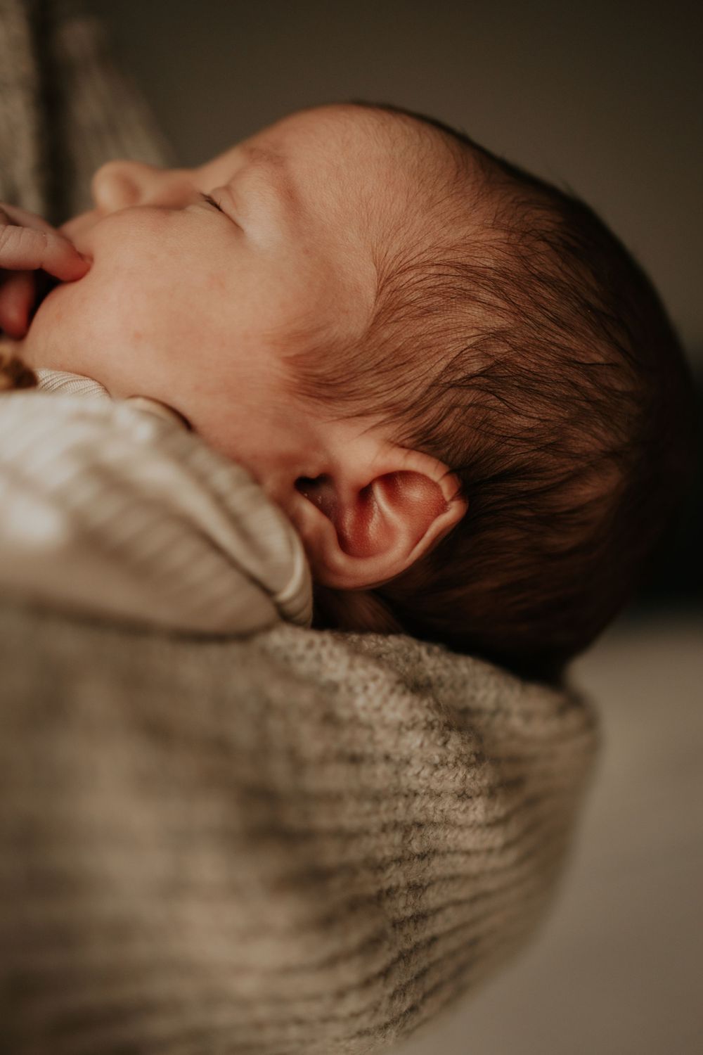 Close-up profile of sleeping newborn baby in soft knit sweater.