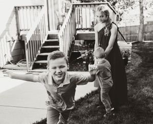 A vintage black and white photo showing playful moments in a backyard with wooden stairs and a fence.