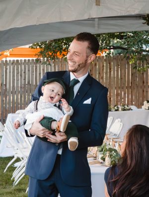A joyful outdoor wedding celebration under a white tent with guests and decorations.