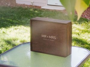 Brown wooden box with 'MR & MRS' text displayed on outdoor table.