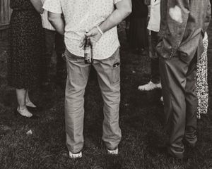 Black and white photo of people's legs and casual attire at an outdoor gathering.